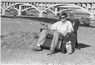 Self portrait of Randy Bass sitting in an easy chair in the Salt River bed, 1987