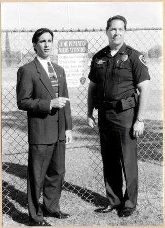 Photo of Neil Giuliano with Police Officer by "Crime Prevention Needs Attention" Sign.
