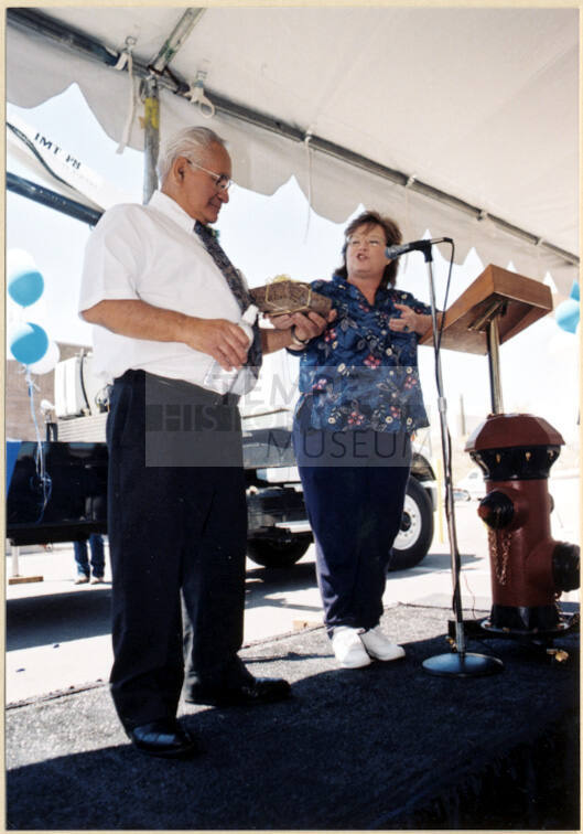 Color photograph of water treatment plant dedication where Johnny Martinez receives present from woman.