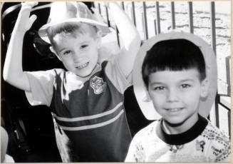 Black and white photograph of children with fire hats at Fire Prevention Day