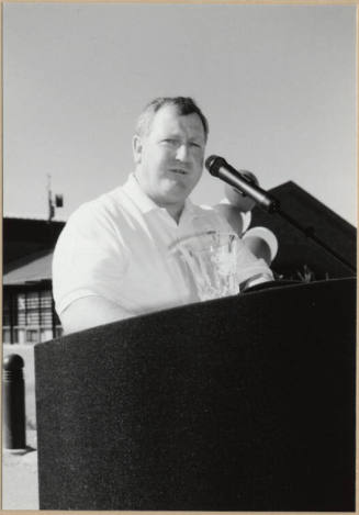 Black and white photograph of man speaking at the dedication of Apache Blvd. Fire Station
