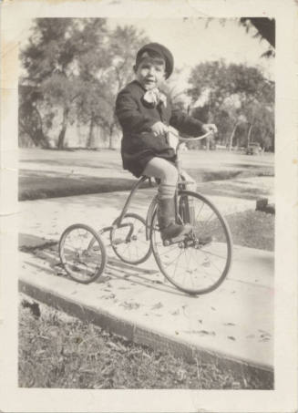 A Boy Riding on a Tricycle in Uniform