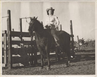 B/W Photo of a Woman on a Horse by a Farm Fence