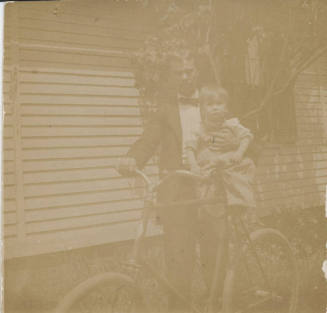 Man Holding Child Beside Bicycle