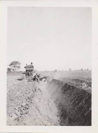 Rear View of Tractor Pulling Ditch Plow
