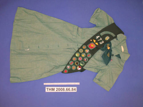 Girl Scout uniform with badge sash and tie