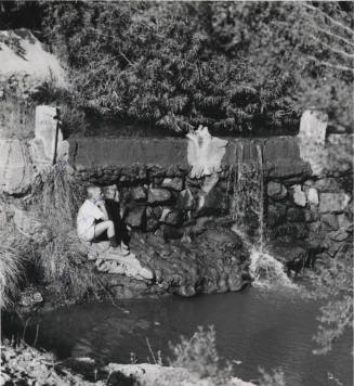 Young Boy Sitting Beside Waterfall and Stream in Moeur Park