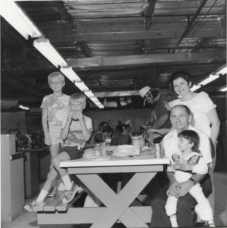 Three Kids and Two Adults Eating at an Indoor Picnic Table