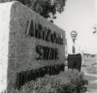 Unidentified man beside a large Arizona State University sign