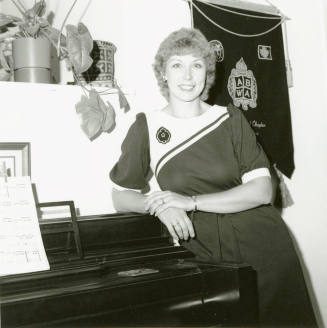Unidentified woman leaning on a piano