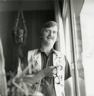 Unidentified man wearing an open vest with pins and sewn patches