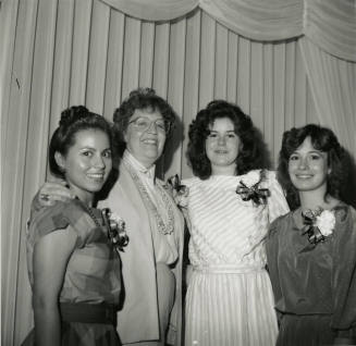 3 young women and an older woman in front of a curtain