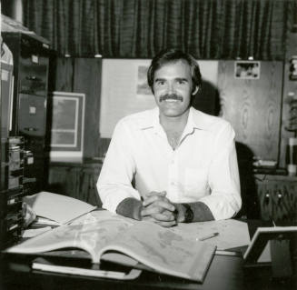 Unidentified Man with Mustache Sitting Behind Desk