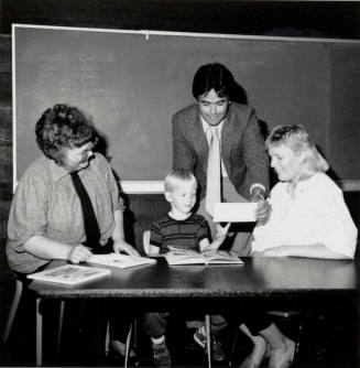Unidentified Group of Adults around a table with a young boy