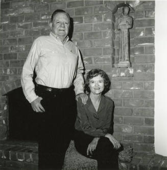 Middle-aged couple in front of fireplace with Saint Francis statue