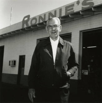 Man stands outside shop labeled "Ronnie's"