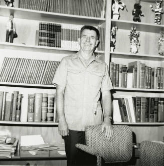 Unidentified man standing in front of a bookshelf