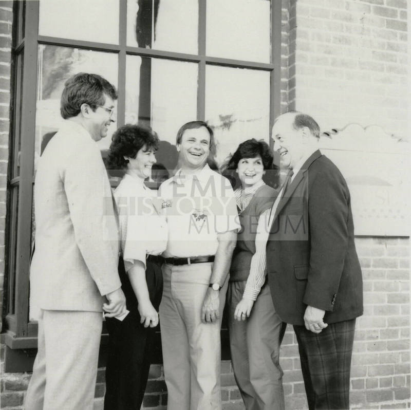 Three unidentified people, Harry Mitchell (center), and Richard Neuheisel (left) outside the Hackett House