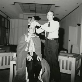 Harry Mitchell putting crown on a mans head.