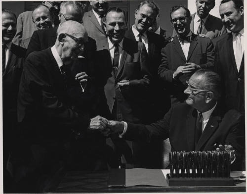 Carl Hayden Shakes Hand of seated L. B. Johnson Signing a Bill
