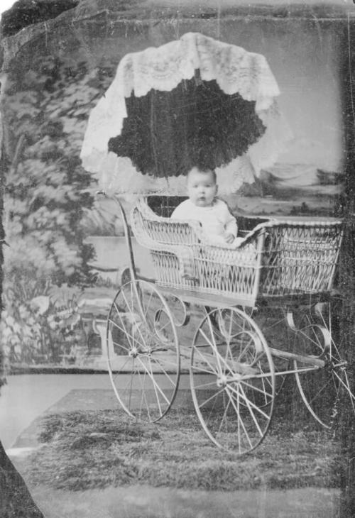 Portrait of Cecil Conser as baby in wicker baby buggy