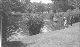 Charles Custis padding a canoe with Charles Harold and Dorothy watching
