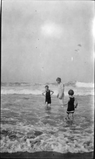 a man and two children wading in ocean