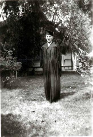 Frank Raymond standing in front of house in a cap and gown