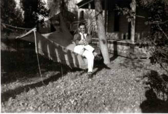 Frank Raymond sitting on hammock under trees