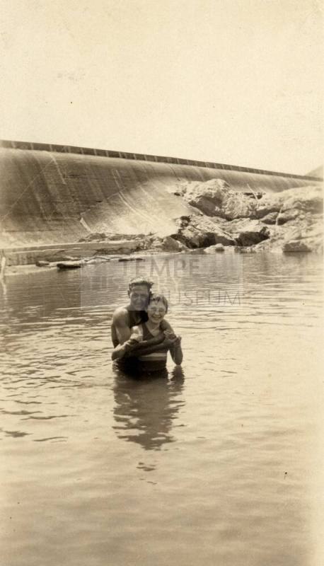 A man and a woman stand in water by the Granite Reef Dam