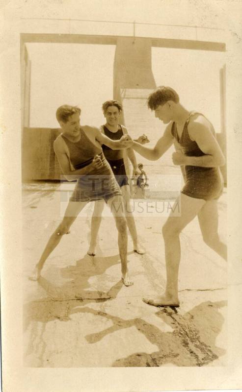 Two young men pretend to fight while a third watches