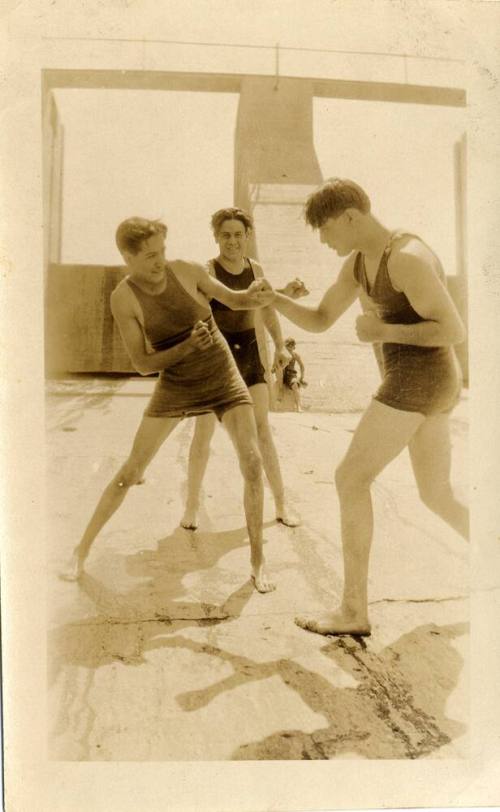 Two young men pretend to fight while a third watches
