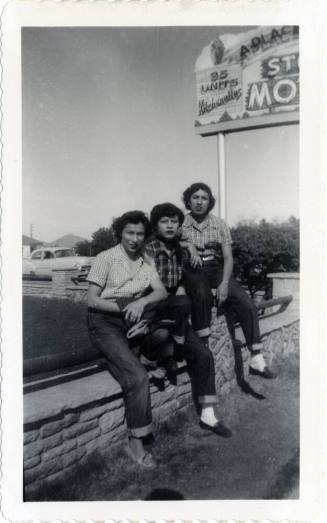 Three friends sitting on fence rail at Van Buren Street motel, Phoenix