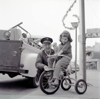 Street Scene with Young Girl on a Tricycle and Uniformed Man on Mill Avenue