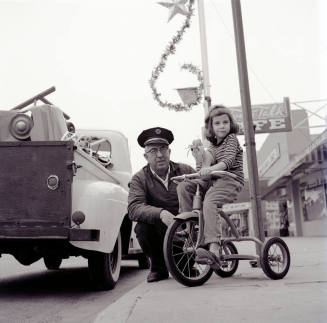 Street Scene with Young Girl on a Tricycle and Uniformed Man on Mill Avenue
