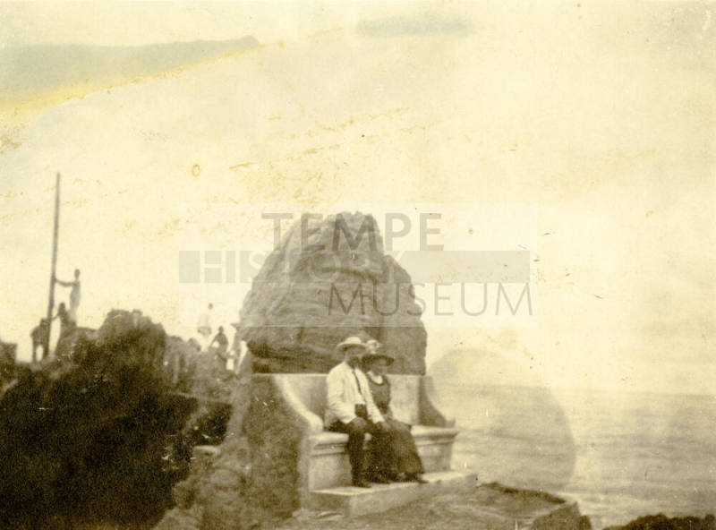 Portrait of Dr. Fenn J Hart and wife Rosa Ann Brown Hart sitting outside on a concrete bench in front of a large boulder