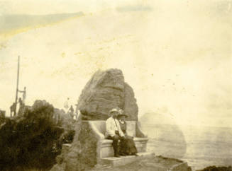 Portrait of Dr. Fenn J Hart and wife Rosa Ann Brown Hart sitting outside on a concrete bench in front of a large boulder