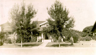 Distant photo of Dr. Fenn J Hart and Rosa Brown Hart in front of their Phoenix home