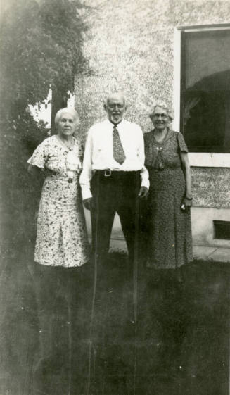 Group photo of Dr. Fenn J Hart standing outside a house with his wife Rosa Brown Hart, and an unkown elderly female