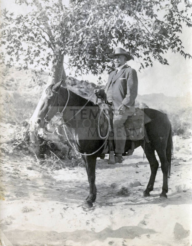 Dr. Fenn J Hart atop a dark horse in the desert