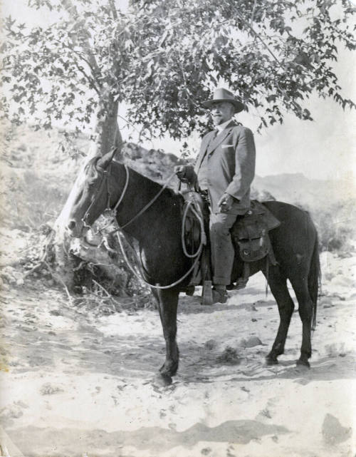 Dr. Fenn J Hart atop a dark horse in the desert