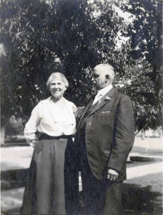 Snapshot of Dr. Fenn J Hart standing under a tree beside his smiling wife Mrs. Rosa Brown Hart