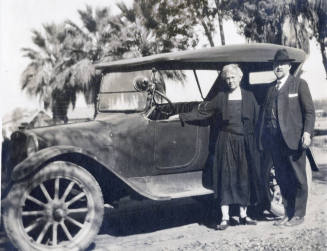 Dr. Fenn J Hart standing outside with his wife Mrs. Rosa Brown Hart in front of his Dodge