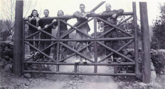 Group photo of Mildred Hart Wilson, daughter of Tempe's first mayor Dr. Fenn J Hart, and her family posing outside together on top of a large wooden gate