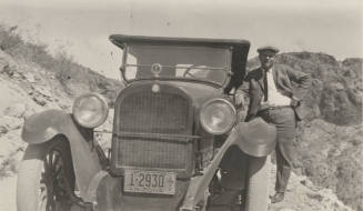 Photo- man standing next to an automobile with a cigar in his right hand