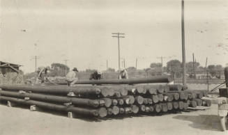 Photo- Men stacking power line poles
