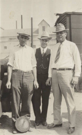 Photo- View of three unidentified men posed in front of a building