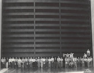 Photo- A row of forty men standing in front of spillway gate at Horse Mesa Dam