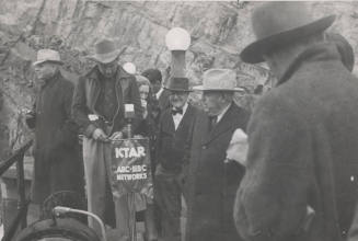 Photo-Group of people standing around a KTAR microphone at Roosevelt Dam