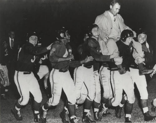 A Football Team Carrying a Coach
